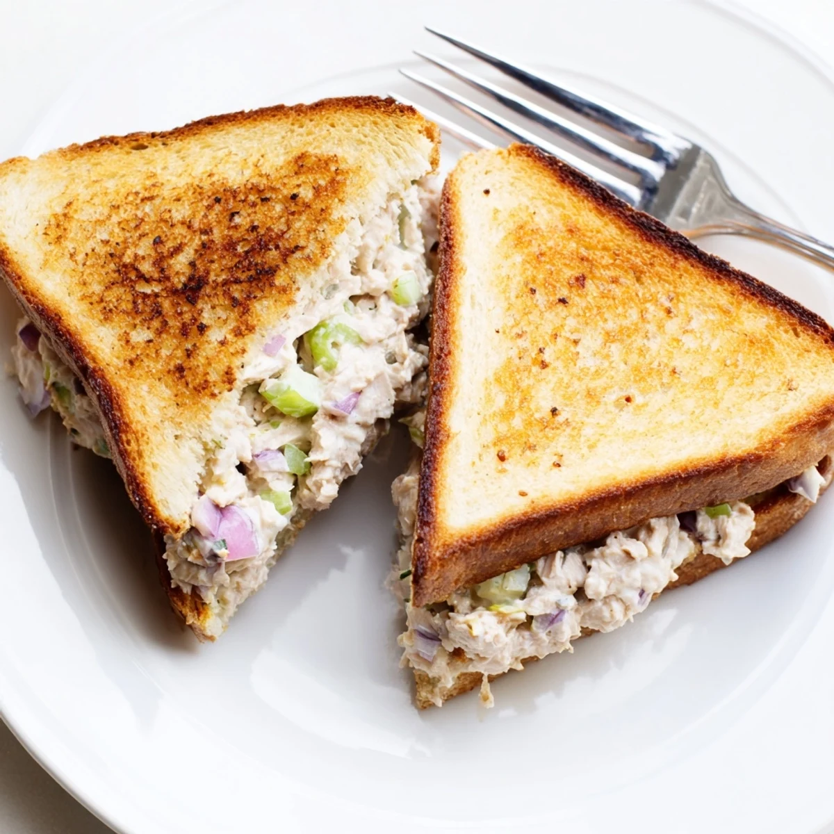 Golden grilled tuna melt sandwich oozing melted Swiss cheese with creamy tuna salad