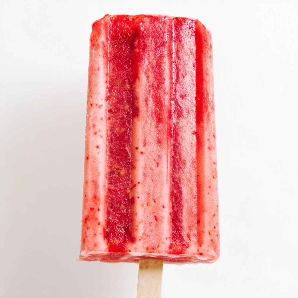 Colorful frozen strawberry watermelon popsicles on wooden sticks with flecks of real berries throughout