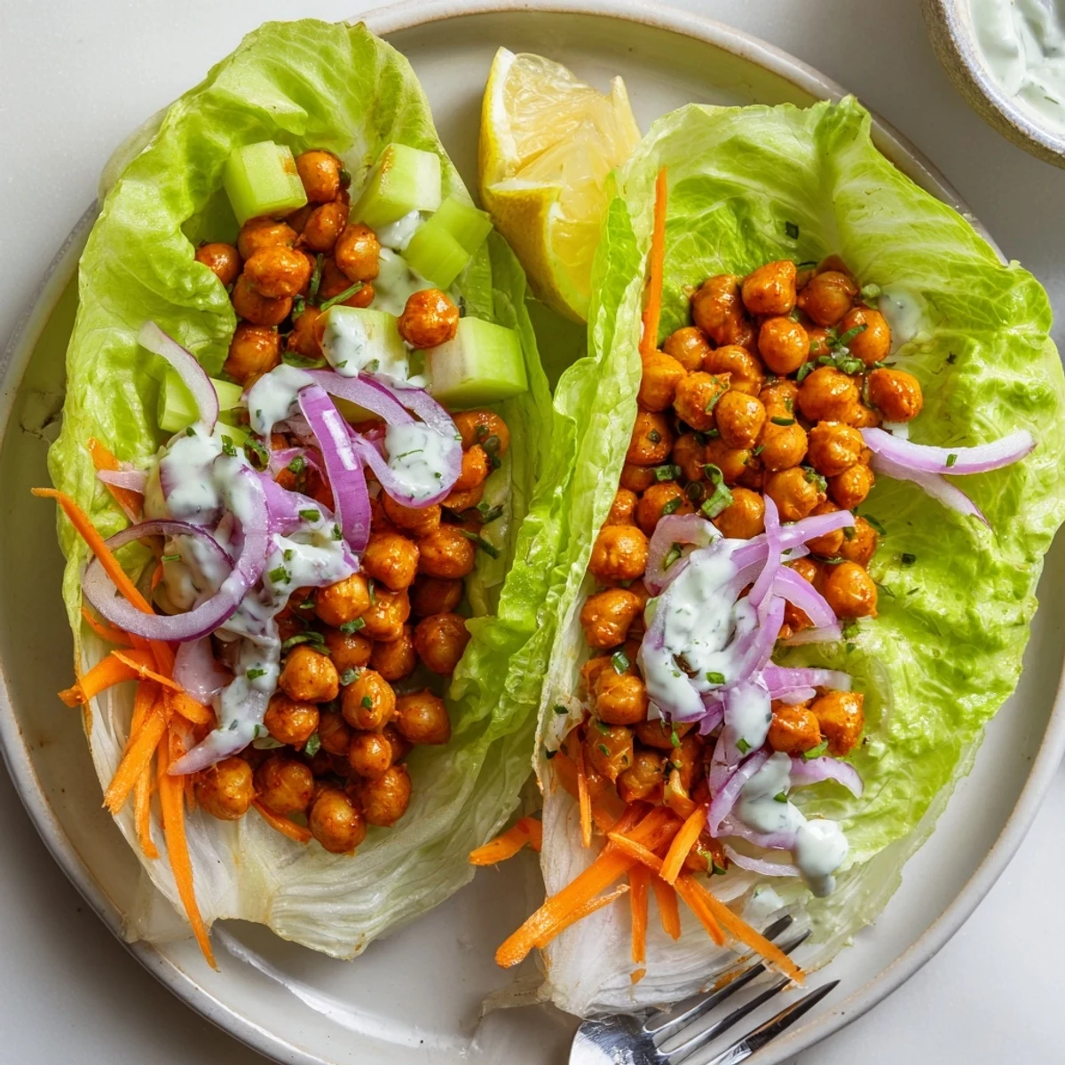 Buffalo Chickpea Lettuce Wraps piled on platter, spicy chickpeas, creamy ranch drizzle  