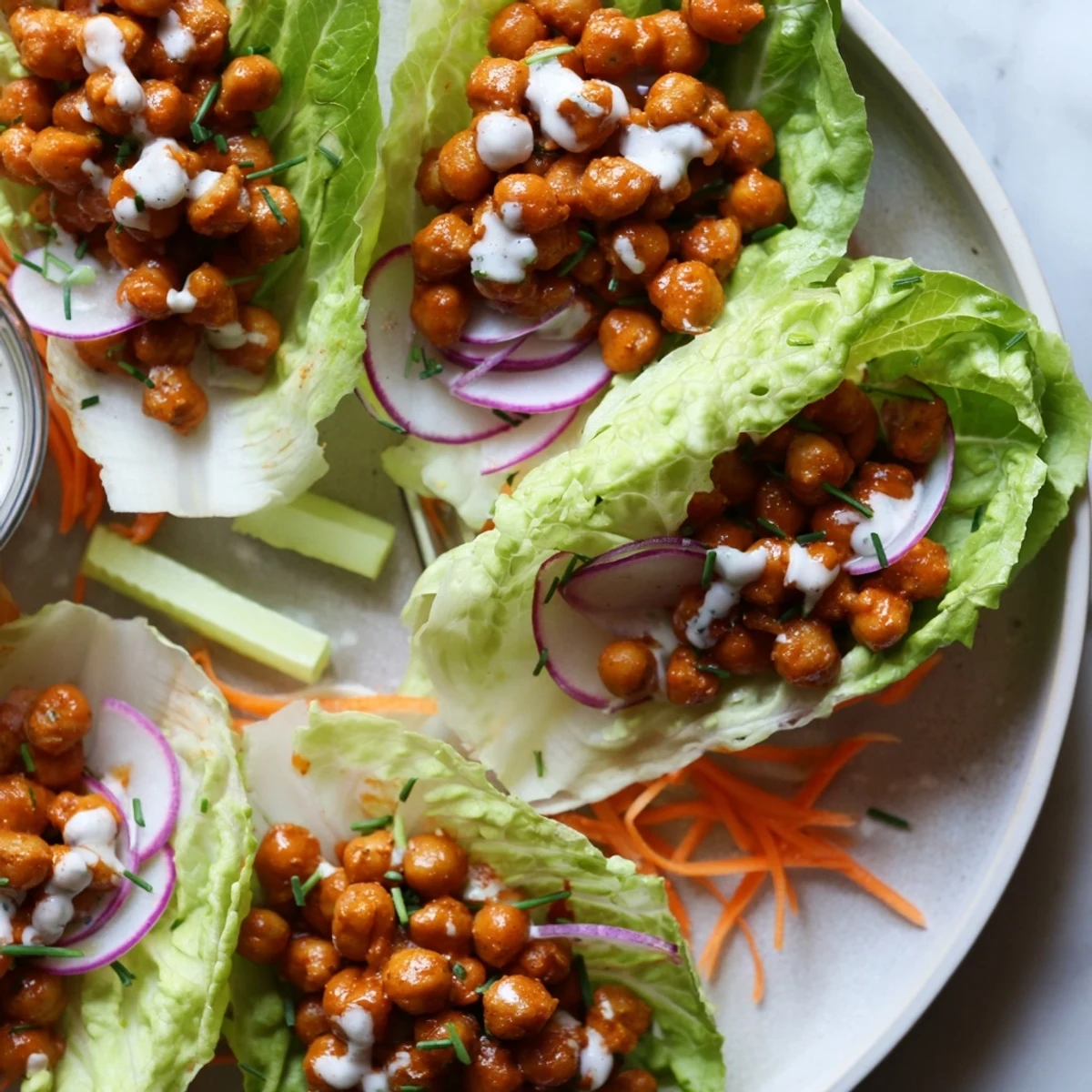 Crisp Buffalo Chickpea Lettuce Wraps with shredded carrots, celery, zesty lemon wedge  