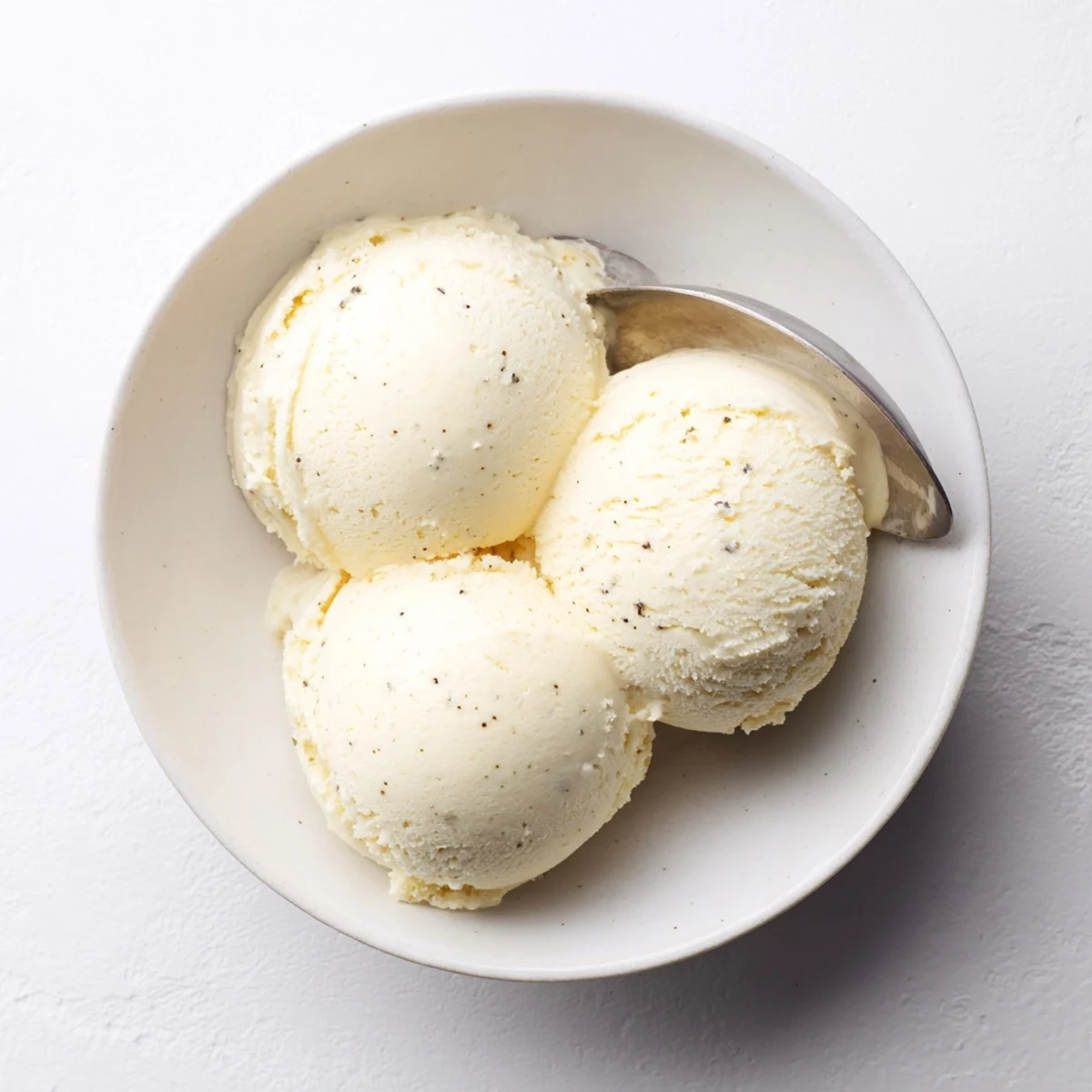 Creamy homemade vanilla ice cream scooped into a chilled glass bowl with fresh berries