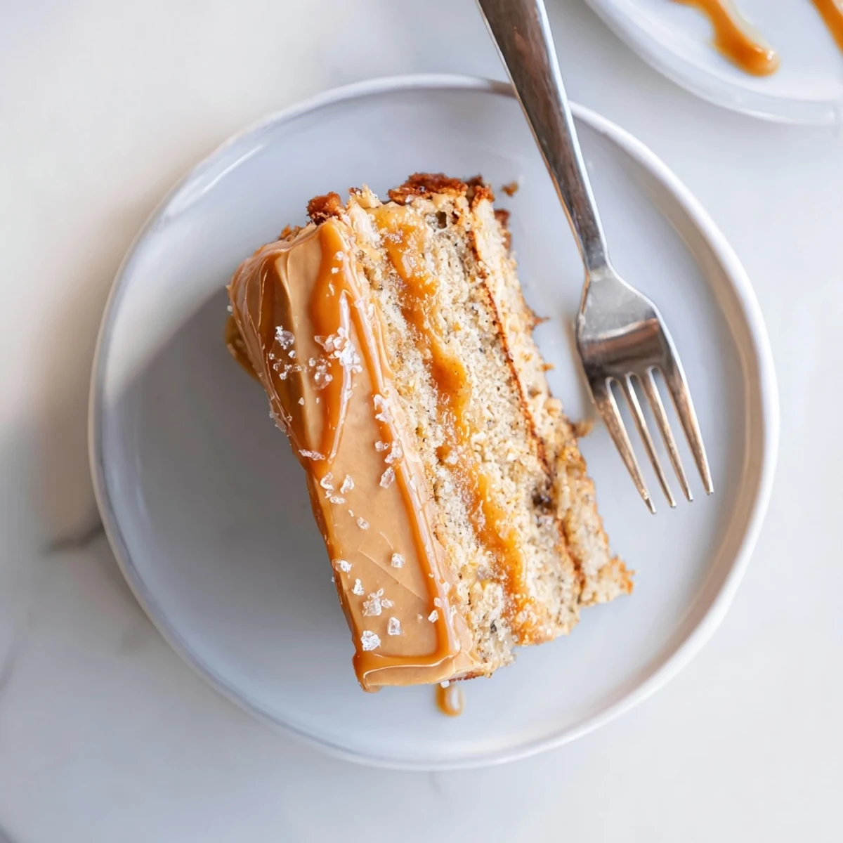 Slice of salted caramel brown butter banana cake revealing tender crumb topped with caramel swirls