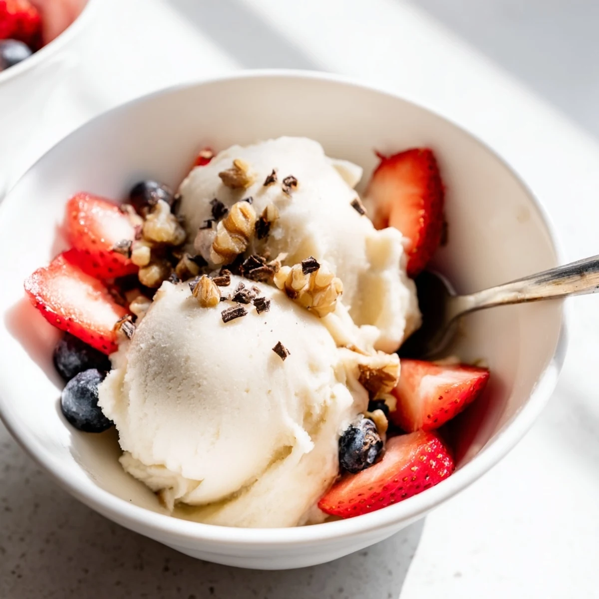 Vegan healthy nice cream swirling in a glass bowl with colorful berry toppings and cacao nibs