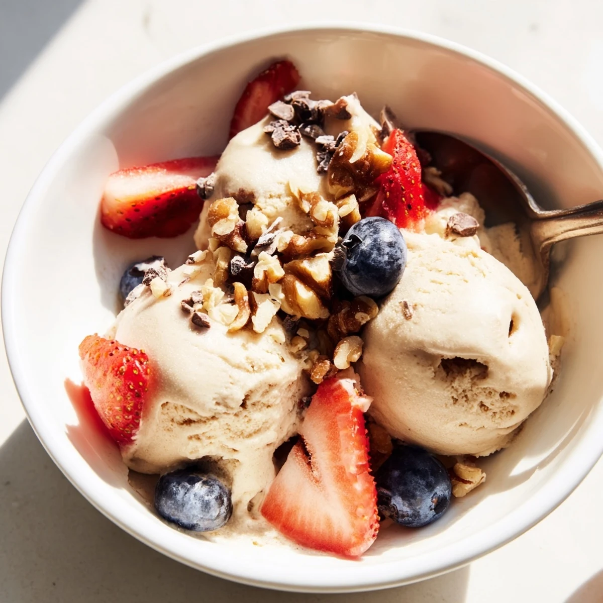 Smooth healthy nice cream topped with chopped nuts and fresh fruit slices on a wooden table