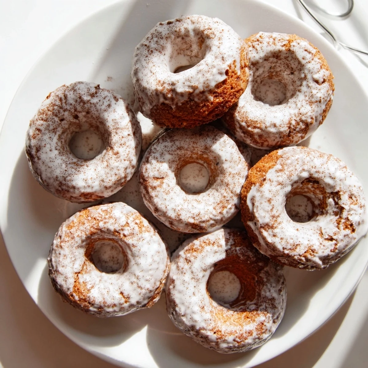 Golden banana bread donuts topped with sweet cinnamon glaze on a white wire rack