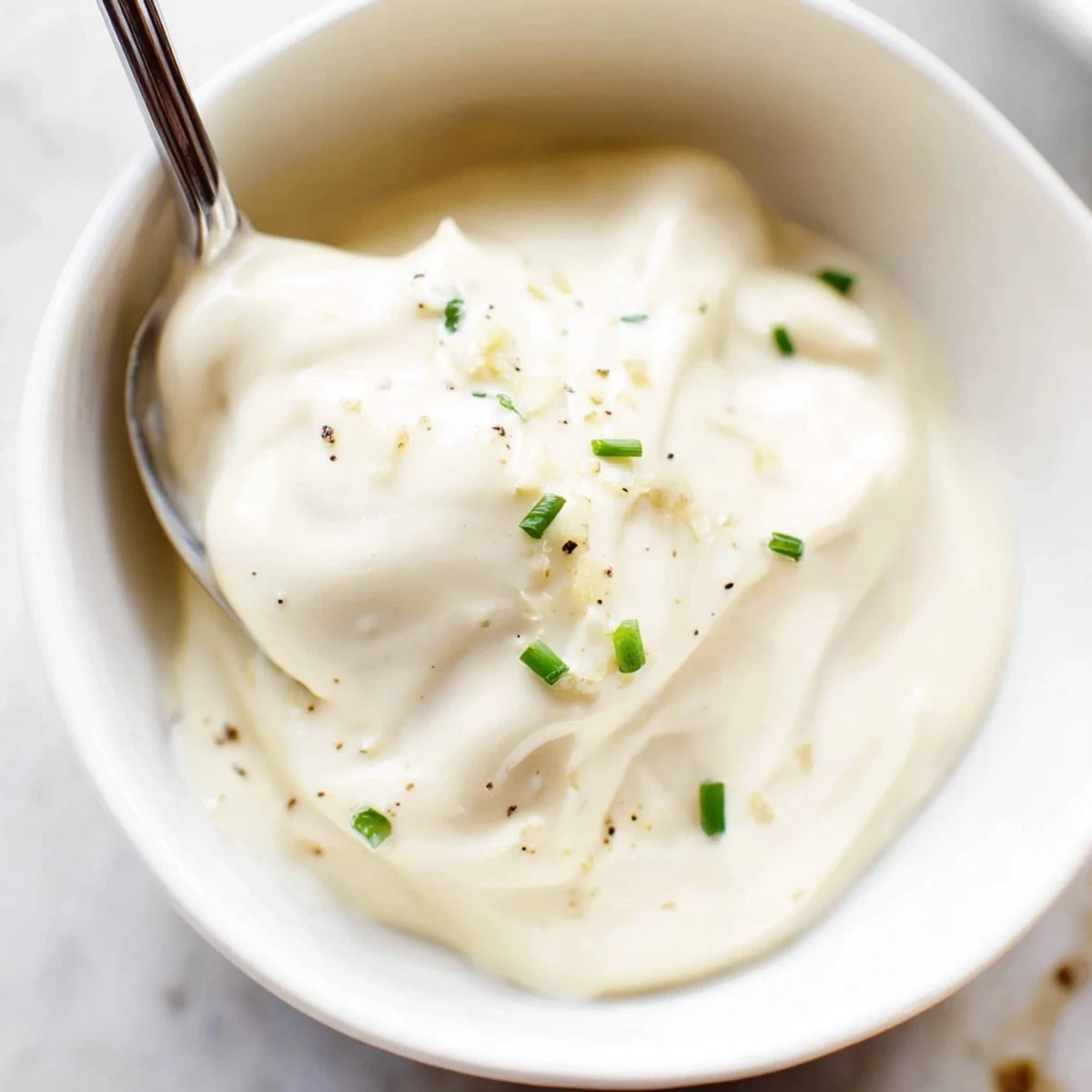 A spoon drizzling Creamy Tangy Sauce over grilled salmon, zesty and smooth