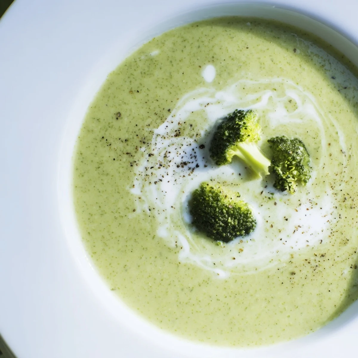 Bright green bowl of homemade Broccoli Soup garnished with toasted seeds