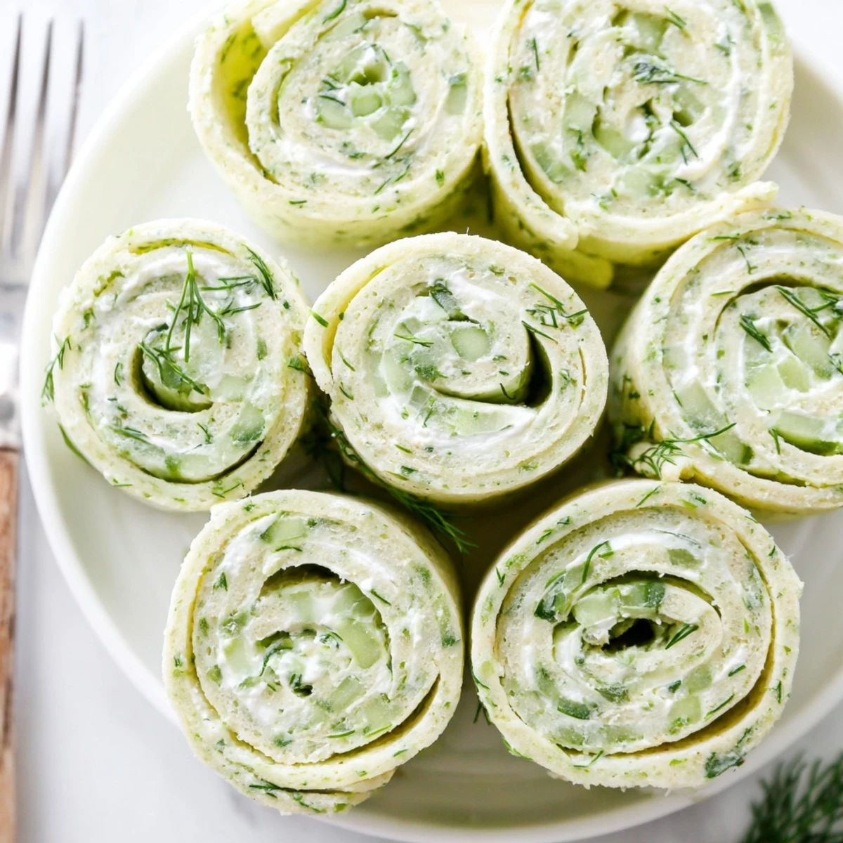 Cucumber And Dill Pinwheels arranged on platter, creamy filling, crisp cucumber rounds