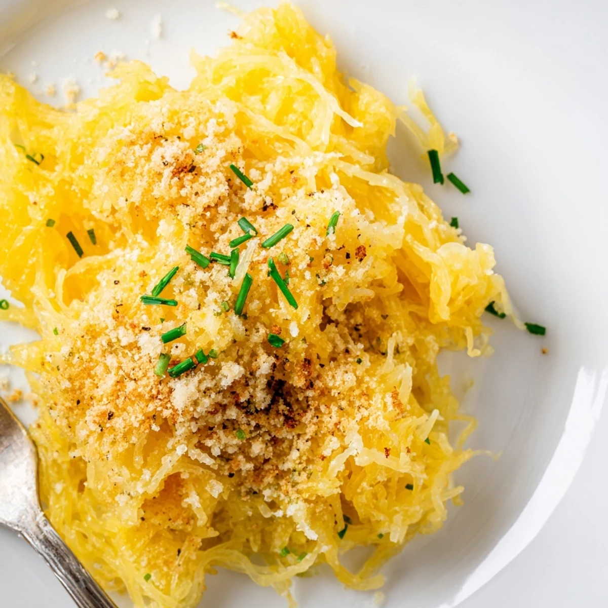 Creamy low-carb spaghetti squash mac and cheese in a white bowl with fresh chive garnish