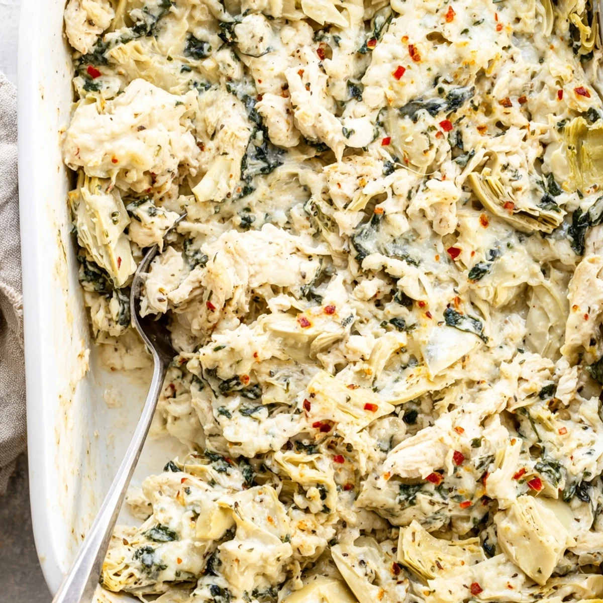 Savory spinach artichoke chicken casserole topped with golden brown cheese and herbs