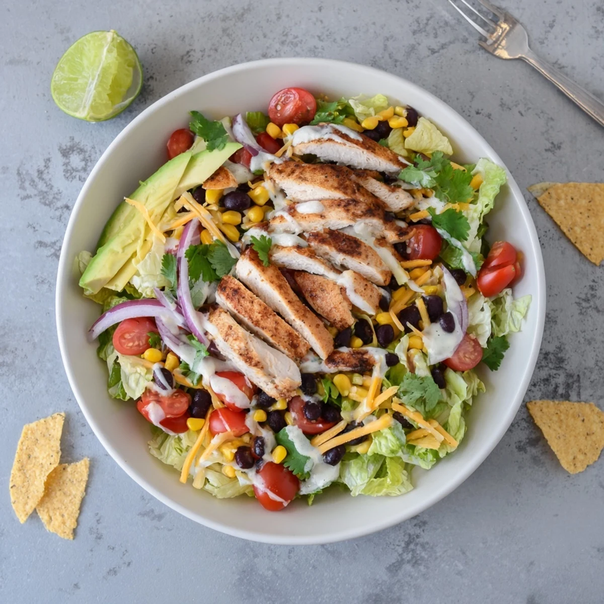 Colorful Southwestern chicken salad bowl with grilled chicken, avocado, beans, and crisp vegetables topped with creamy lime dressing