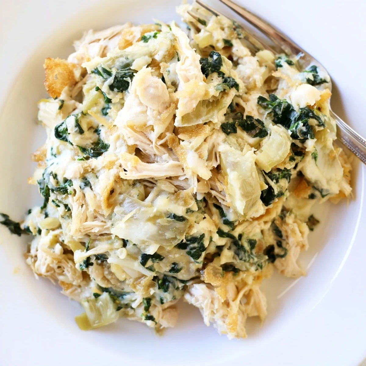 Hearty Spinach Artichoke Chicken Casserole spooned steaming onto plate, creamy, savory
