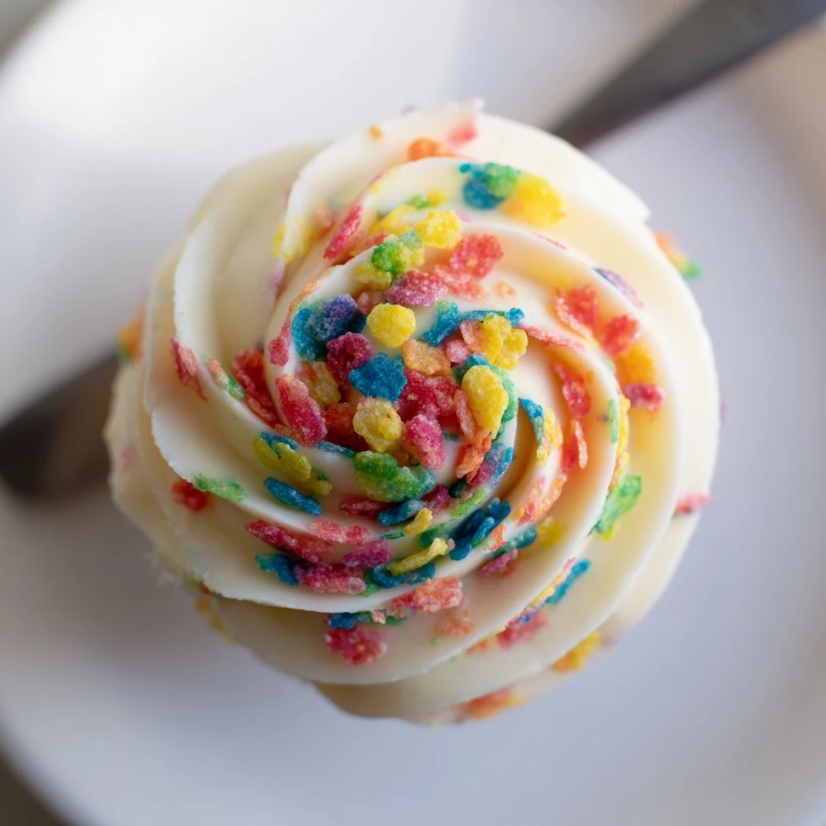 A spoonful of Fruity Pebbles Cereal Frosting, bright, creamy with crispy bite.