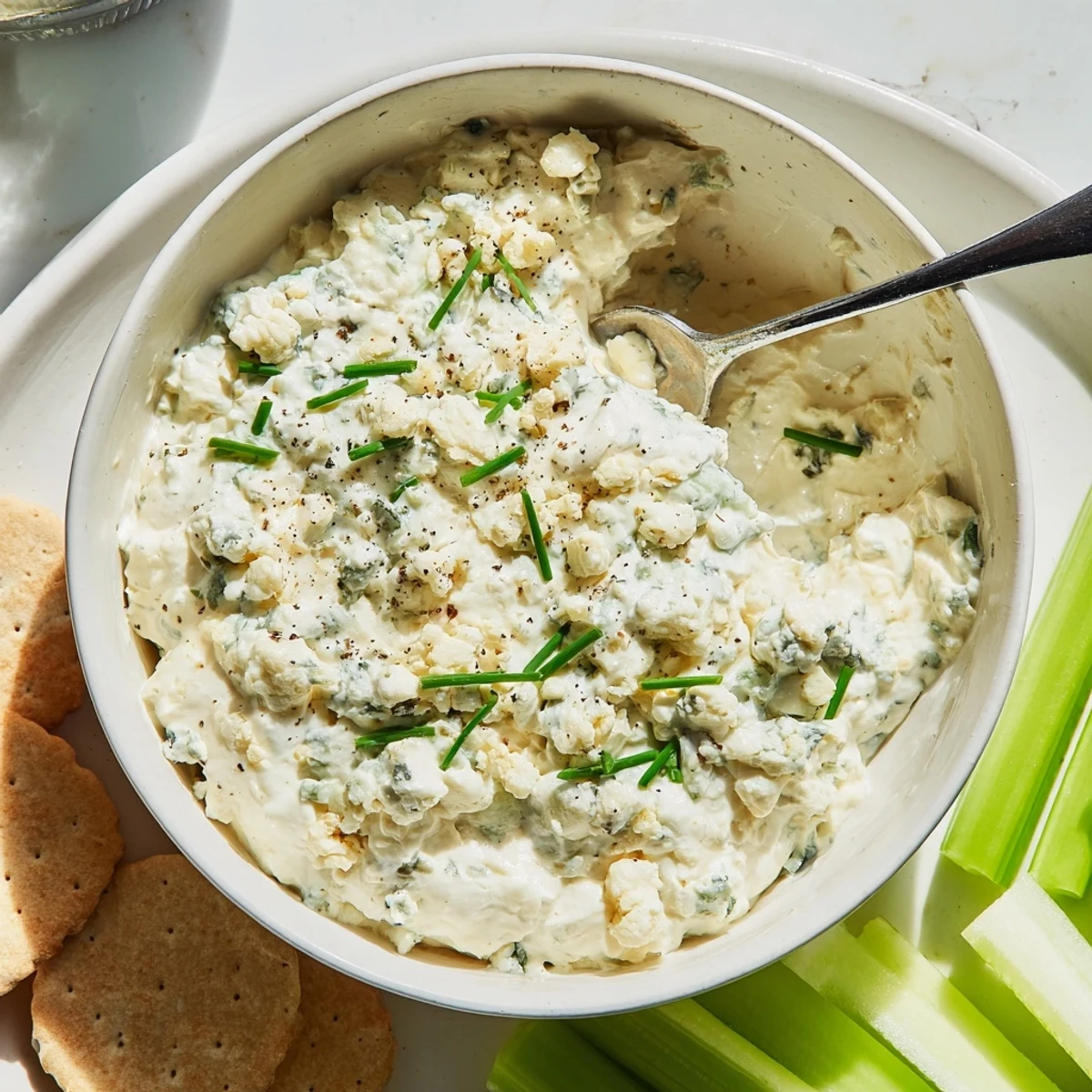 Rich blue cheese dip in a rustic bowl surrounded by colorful fresh vegetable sticks