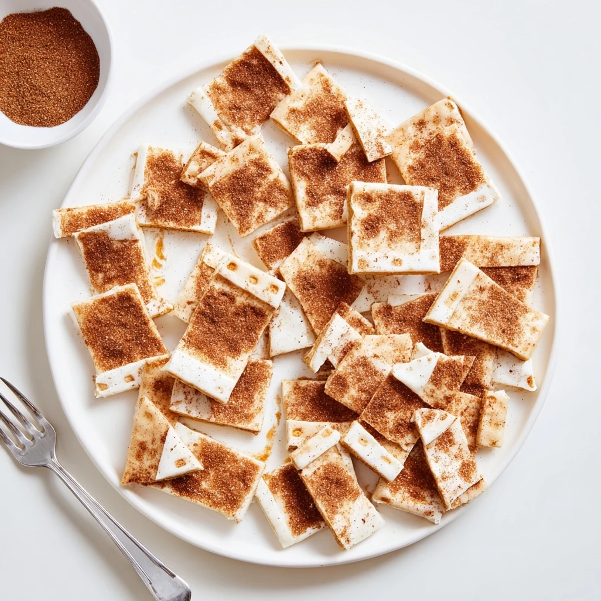 Golden Churro Saltine White Toffee pieces dusted with warm cinnamon sugar on a rustic cutting board.