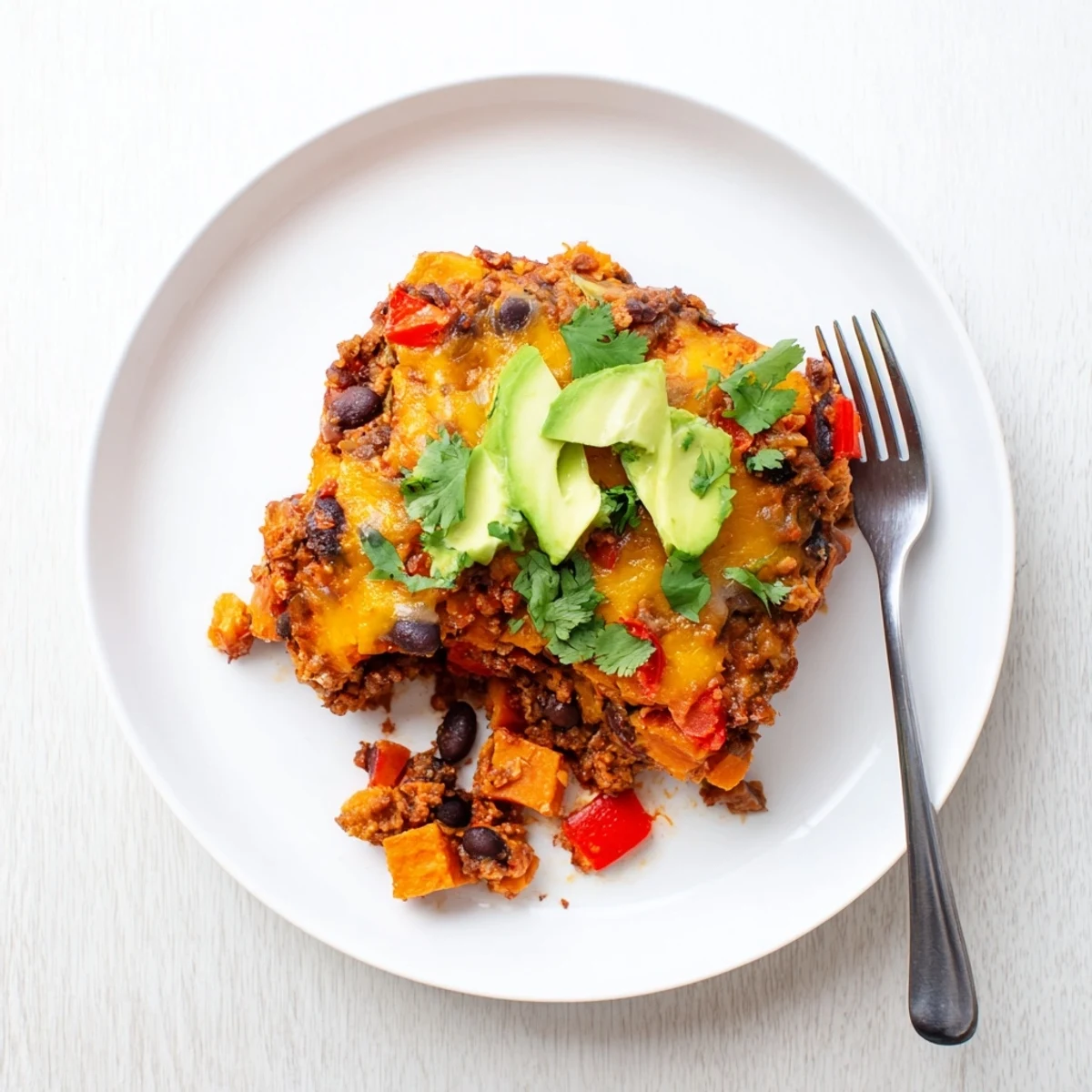 Sweet potato turkey black bean bake topped with melted cheddar and fresh cilantro sprigs