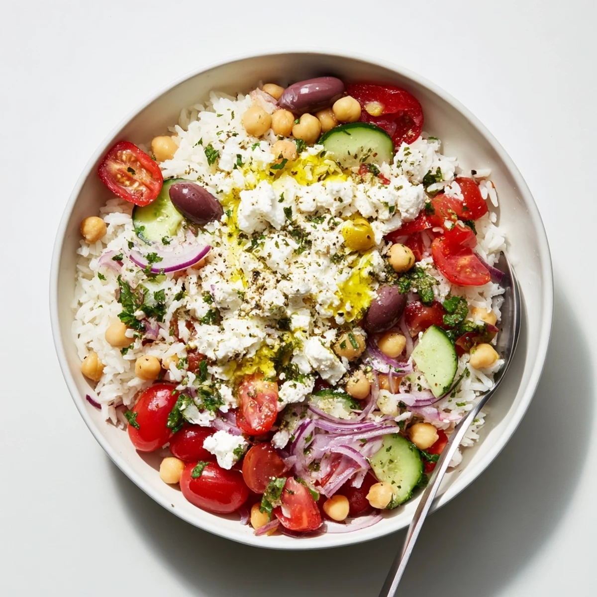Colorful Mediterranean Rice Bowl topped with fresh cucumbers, tomatoes, chickpeas, and crumbled feta
