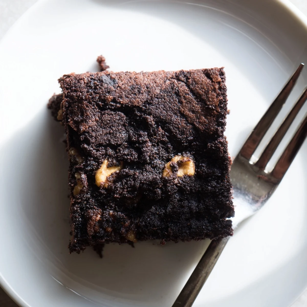 Dark chocolate brownies studded with walnuts, showing a dense fudgy center sliced into generous pieces
