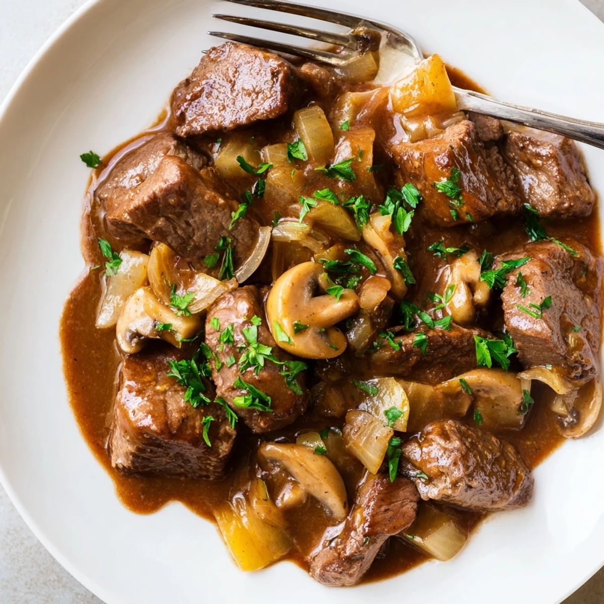 Hearty weeknight steak tips and gravy in a cast iron skillet with mushrooms
