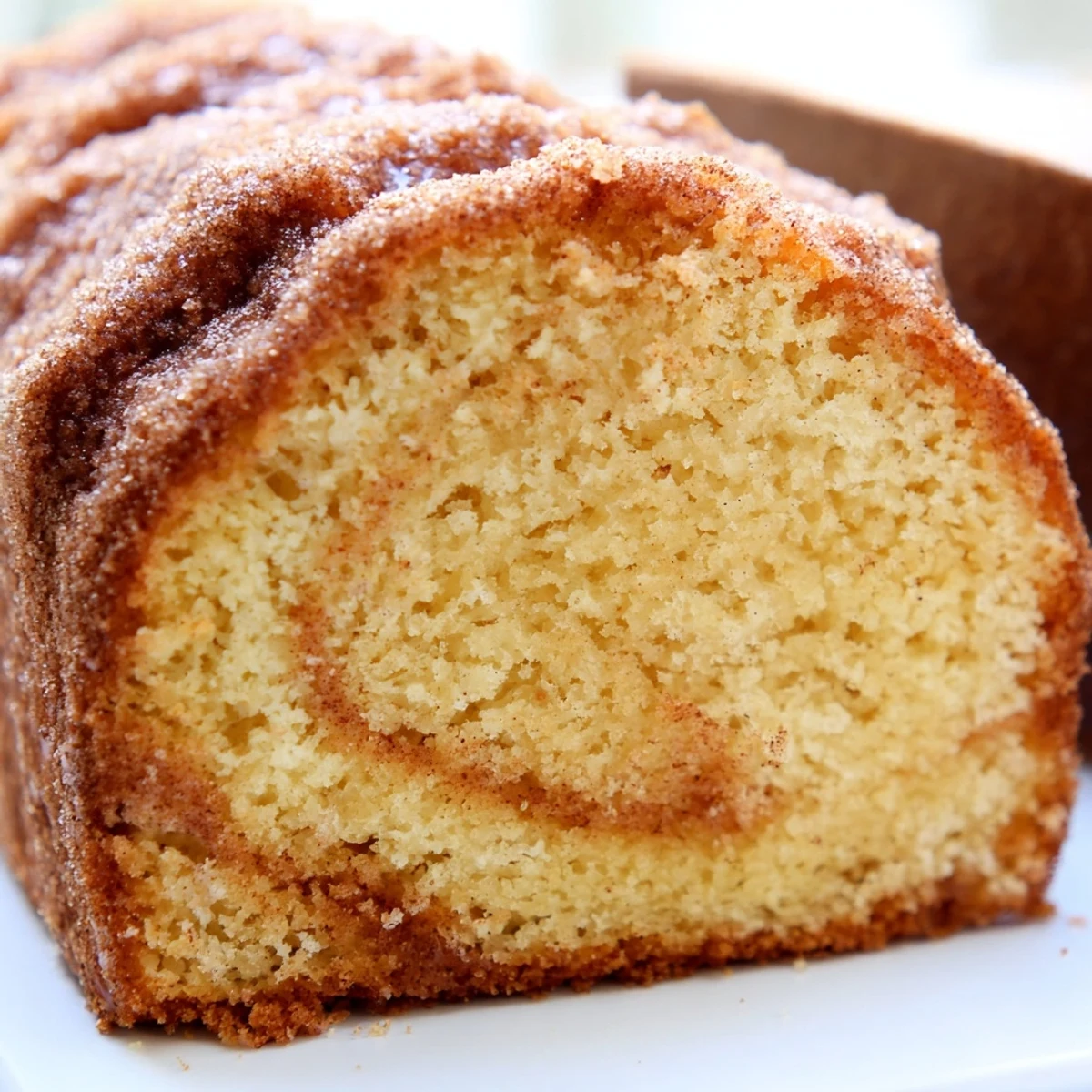 Warm cinnamon donut loaf sliced thick with a golden cinnamon-sugar crust on a rustic cutting board