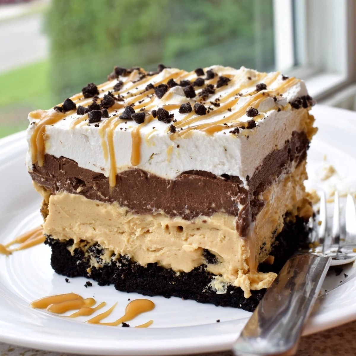 No-bake peanut butter layered delight topped with chocolate shavings and a peanut butter drizzle