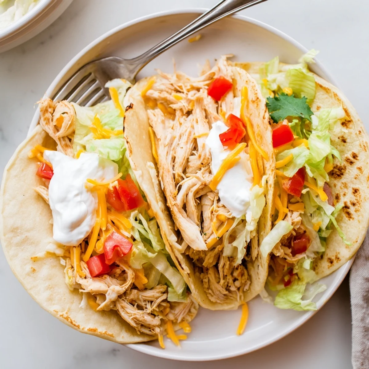 Juicy shredded Slow Cooker Ranch Chicken Tacos loaded with sour cream lettuce and cheddar
