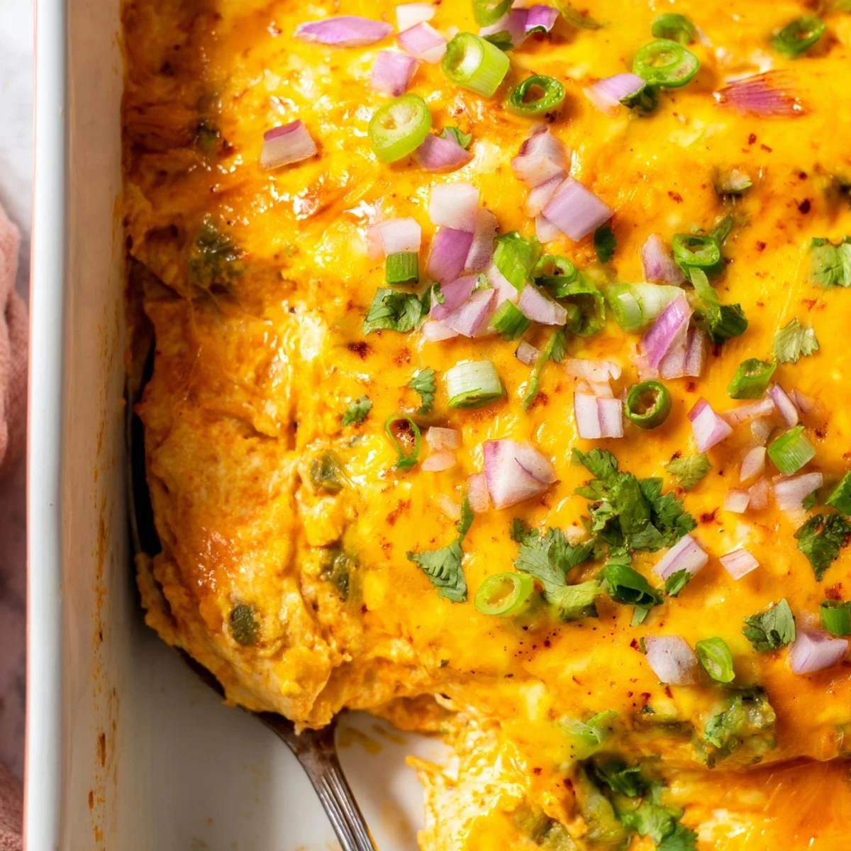 Steaming spoonful of jalapeno buffalo chicken casserole with melted cheese and green onions