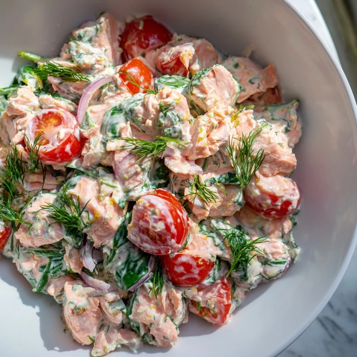 Creamy leftover salmon recipe in a golden skillet with wilted spinach and cherry tomatoes