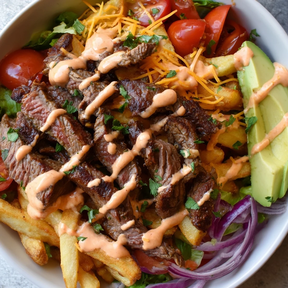 Hearty steak strips and crispy fries bowl drizzled with smoky paprika sauce