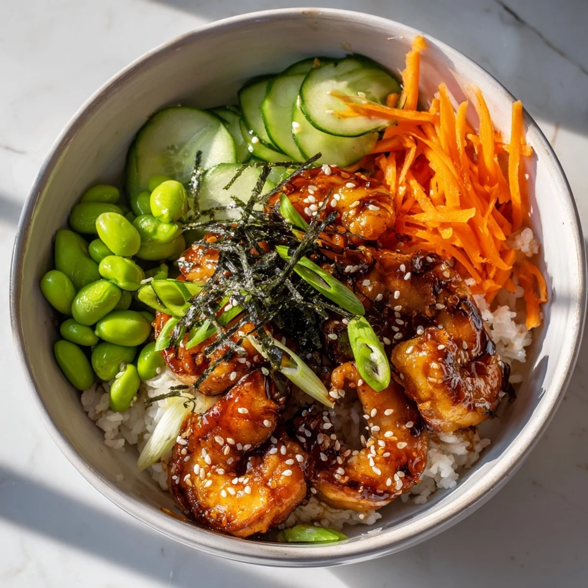 Glossy teriyaki shrimp arranged in a bowl with jasmine rice and crunchy edamame