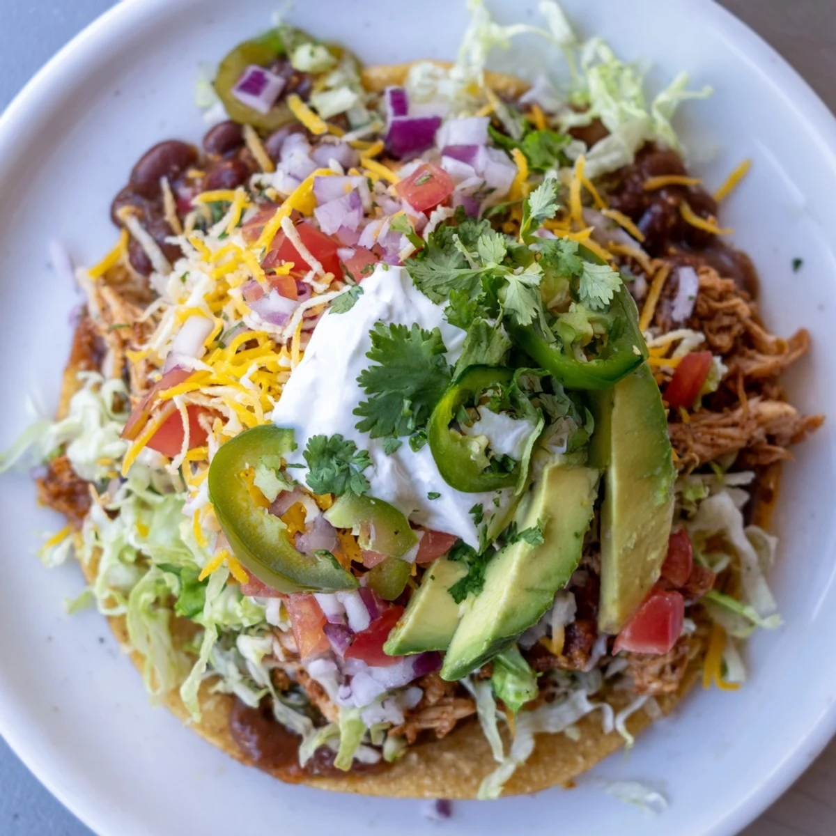 Golden Chicken Tostadas topped with fresh veggies and creamy avocado slices  