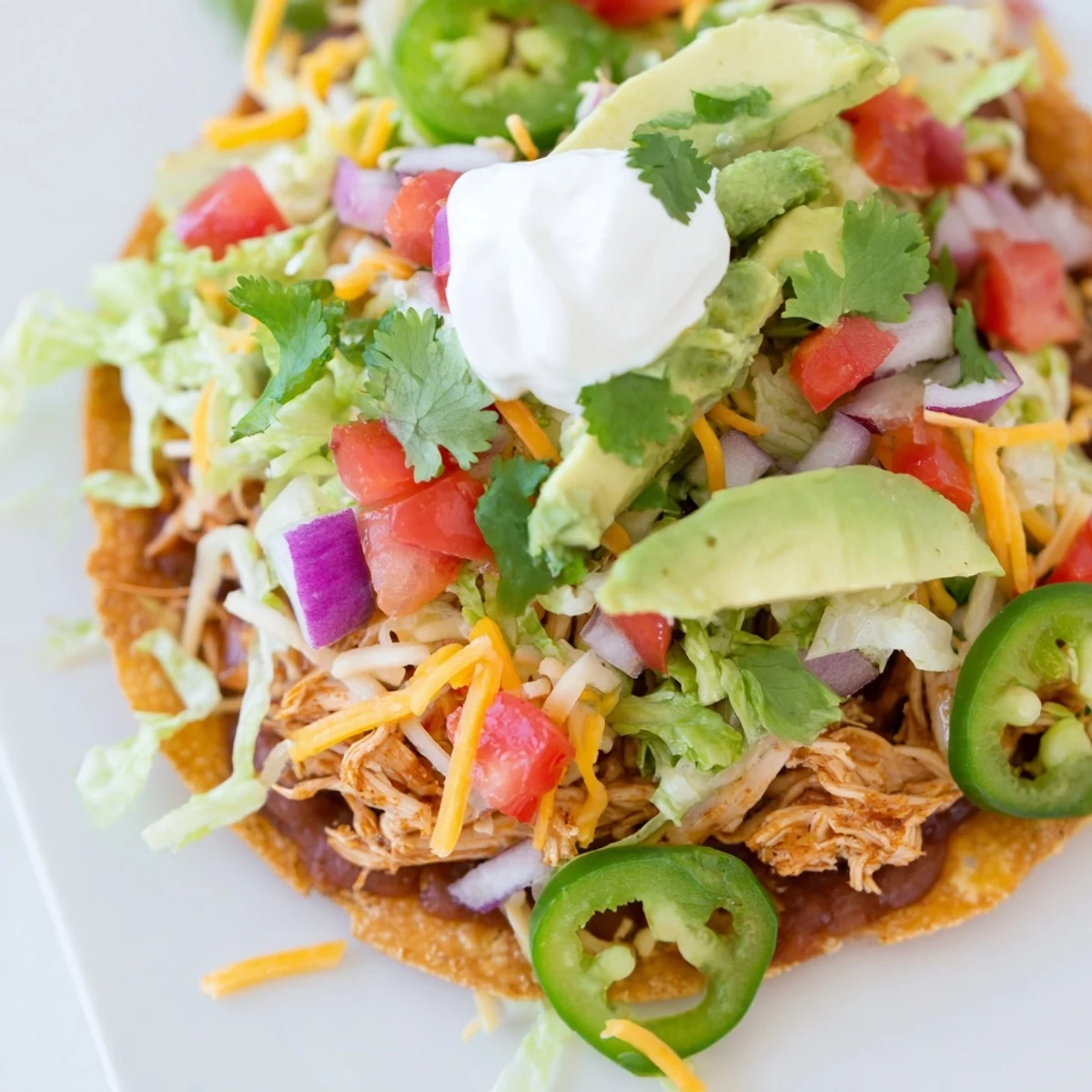 Vibrant Chicken Tostadas served with lettuce, cheese, and zesty lime wedges