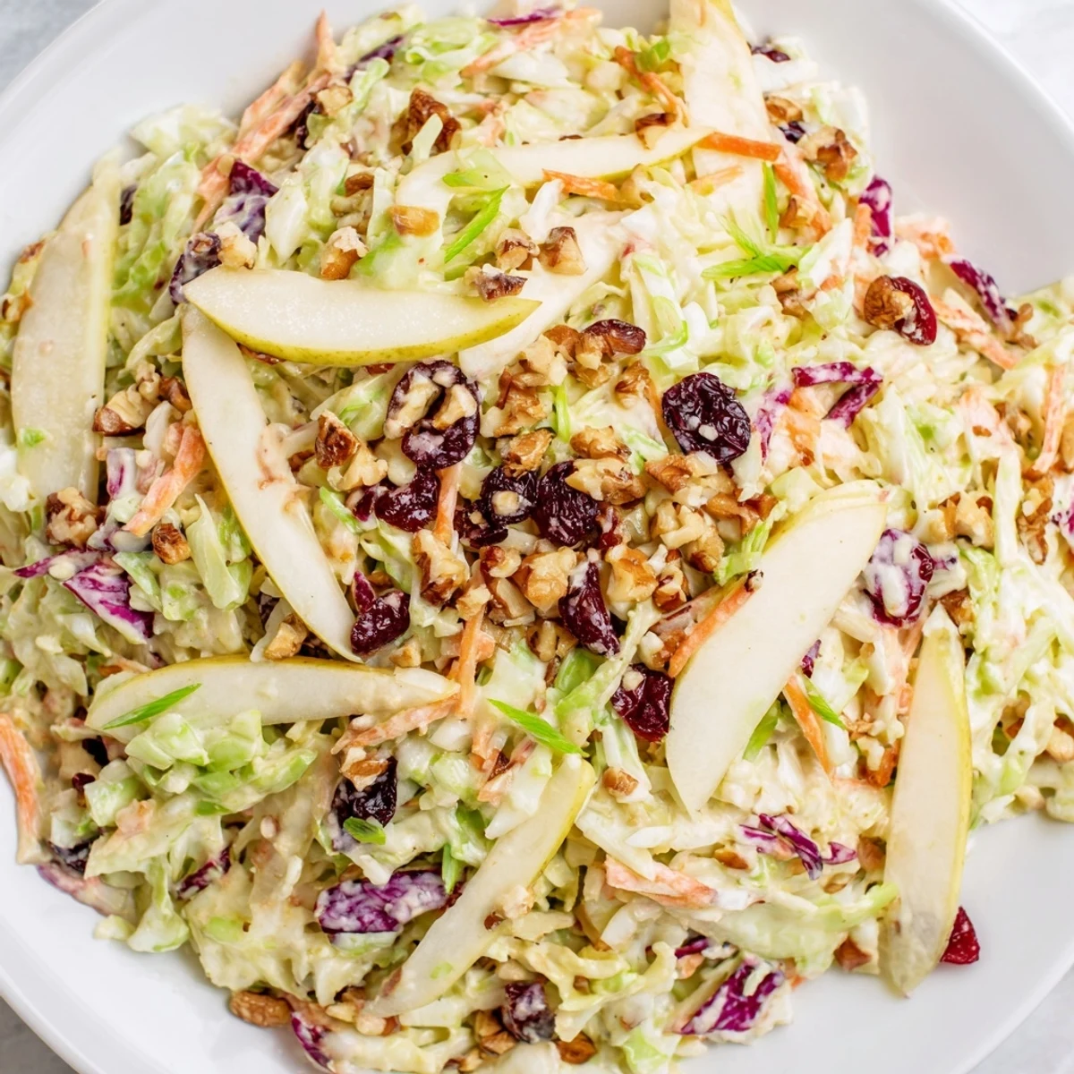 Colorful cranberry apple coleslaw bowl featuring tart cranberries, crunchy carrots, and creamy dressing.