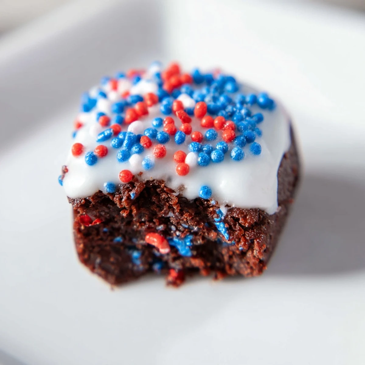 Festive brownie bites drizzled with white glaze and colorful decorations.  