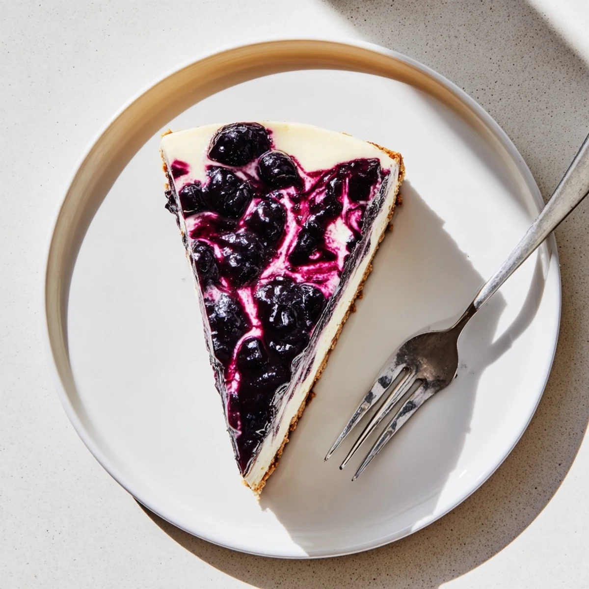 Homemade blueberry cheesecake showing swirls of tangy topping over smooth filling.
