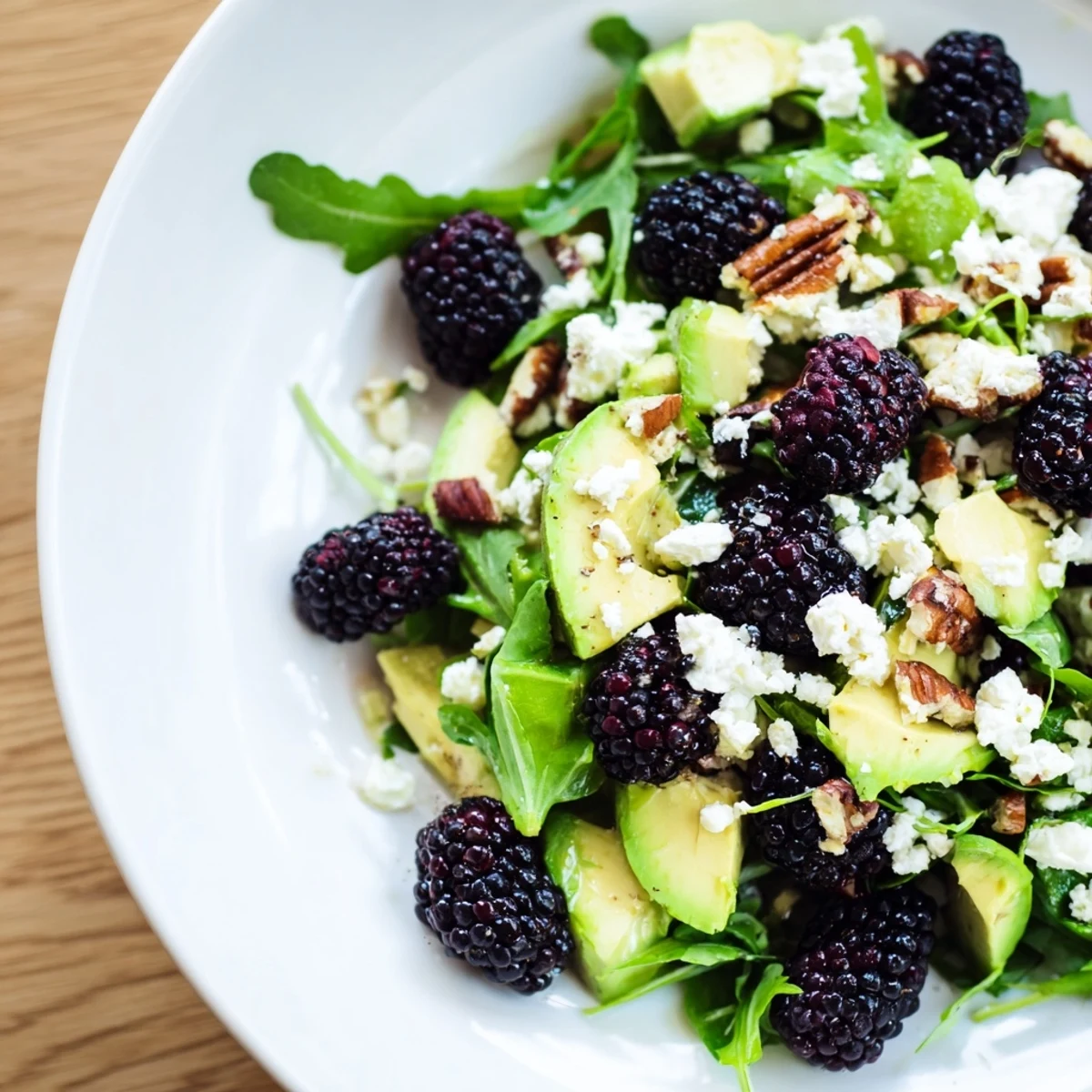 Fresh blackberry avocado salad drizzled with zesty honey-lime dressing over arugula.  