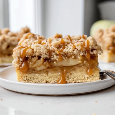Warm caramel apple crumb bars cut into squares showing tender cinnamon apple layers inside
