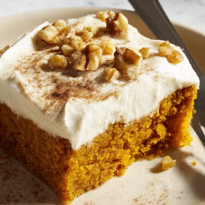 Thick pillowy cream cheese frosting spread over warm cinnamon spiced pumpkin bars