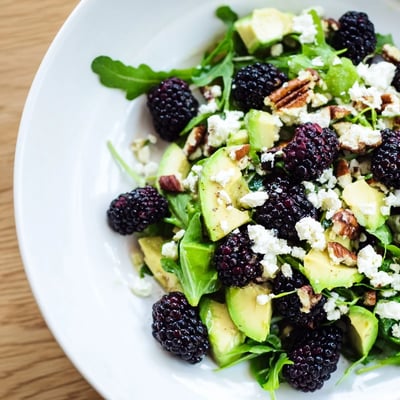 Fresh blackberry avocado salad drizzled with zesty honey-lime dressing over arugula.  